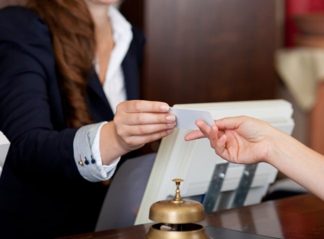 smiling female receptionist passing card to guest